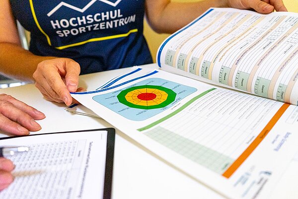 zwei Personen betrachten einen Hefter mit einer Grafik zum Rückenscreening