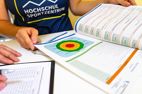 zwei Personen betrachten einen Hefter mit einer Grafik zum Rückenscreening